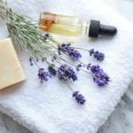 Handmade bath soap, essential oil, fresh lavender flowers, white towel on a marble countertop